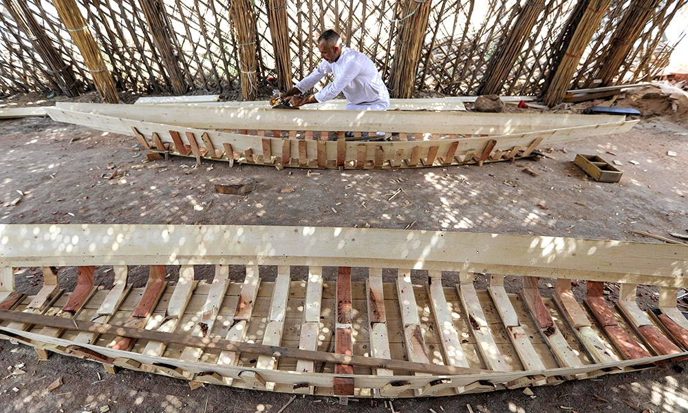 A carpenter shaves wood as he builds a traditional 'meshhouf' wooden boat at a workshop.