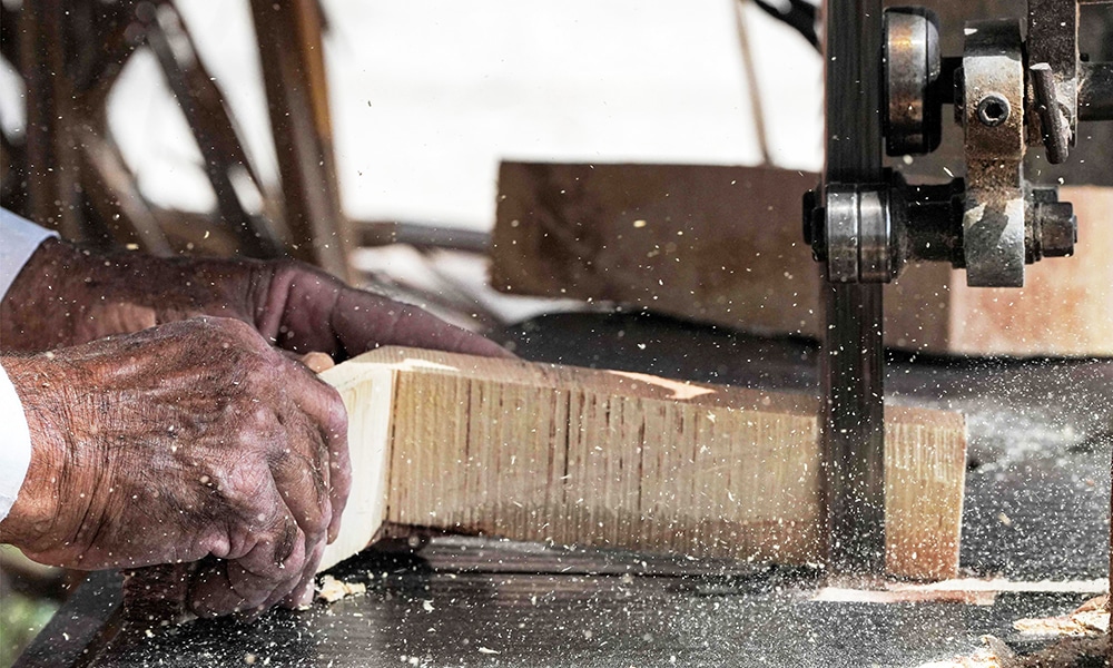 A carpenter uses an electric saw to cut wood as he builds a traditional 'meshhouf' wooden boat at a workshop.