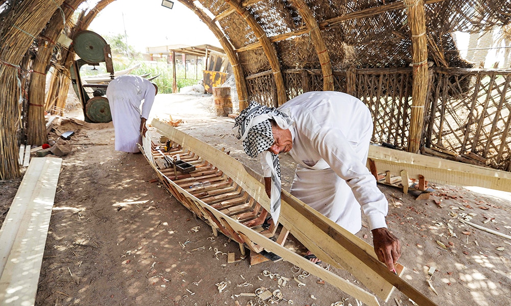 A carpenter measures a plank as he builds a traditional 'meshhouf' wooden boat at a workshop.
