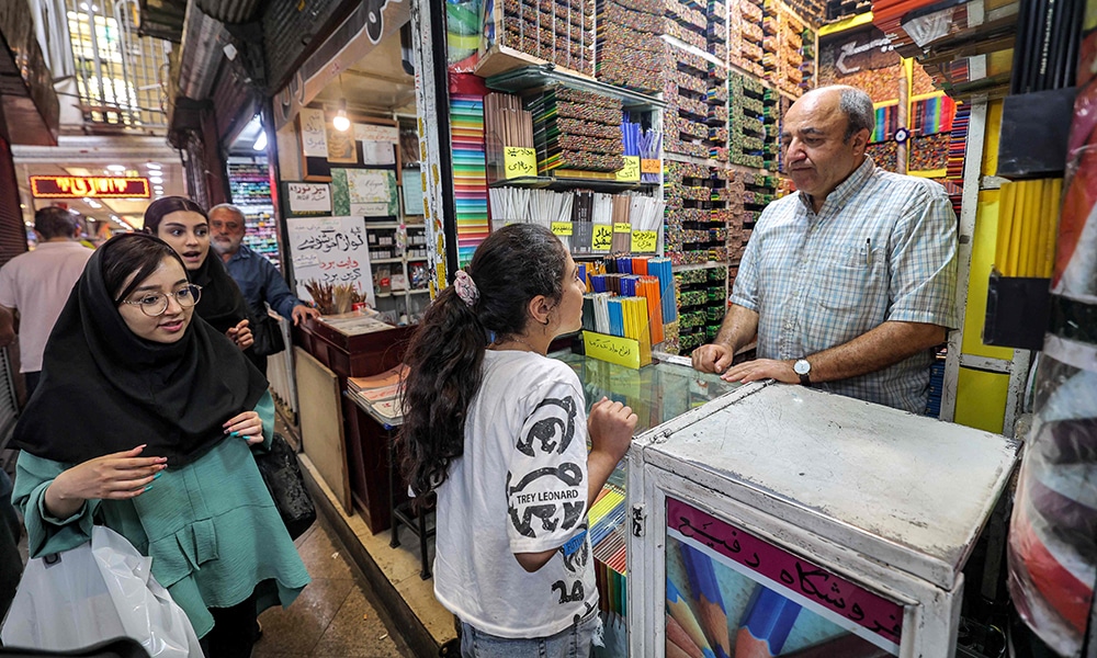 Mohammad Rafi, a seller of coloured pencils at the Grand Bazaar in Tehran, assists a student girl customer at his shop.