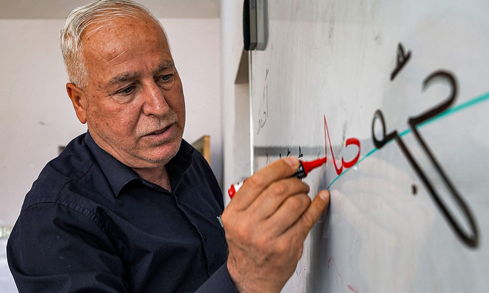 Syriac language teacher Salah Sarkis writes on a whiteboard as he gives a class at the Ashurbanipal Syriac School.