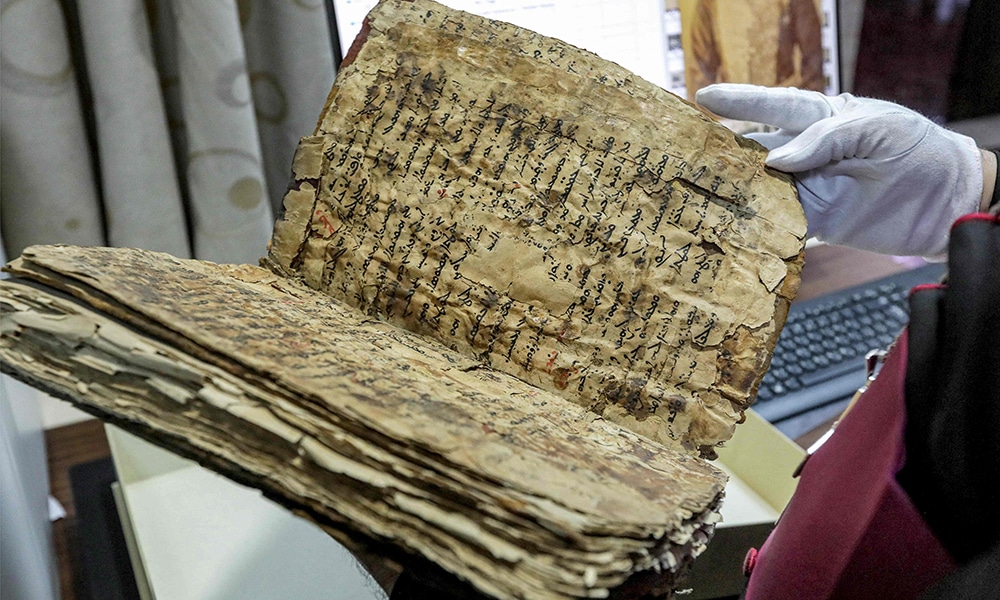 The Chaldean Catholic Archbishop of Mosul Michaeel Najeeb holds an old damaged Syriac-language Christian codex at the Eastern Manuscript Digitisation Centre (CNMO) in Arbil.