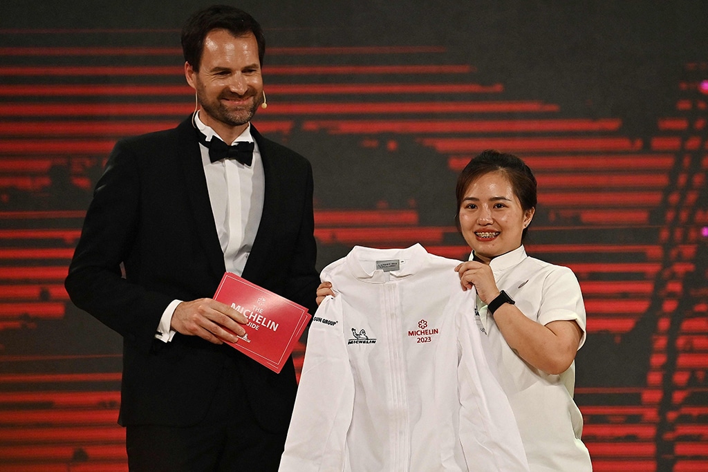 Gia Restaurant Chef and Co-founder, Sam Tran (right) holds her Michelin Star winner chef's whites at the Michelin Guide Ceremony in Hanoi.