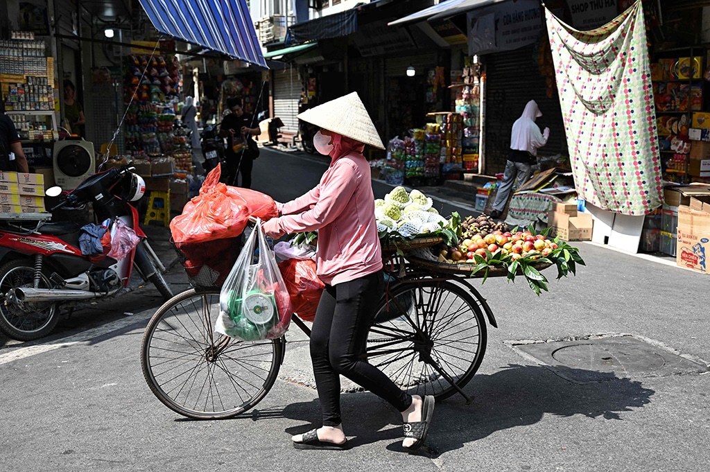 A street vendor pushes her bicycle carrying fruits in Hanoi.