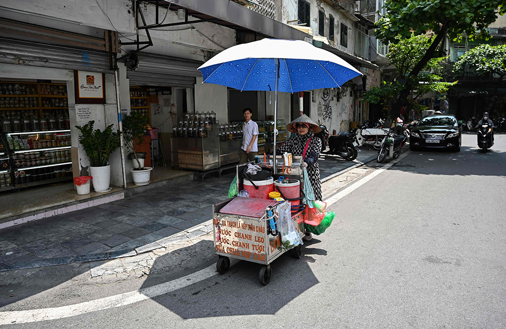 Street vendor Vu Thi Phuong pushes a trolley to sell coffee and soft drinks in Hanoi.