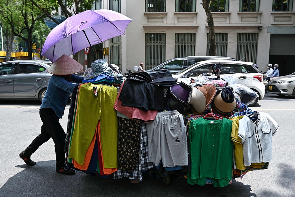 A street vendor pushes a cart of clothes in Hanoi.