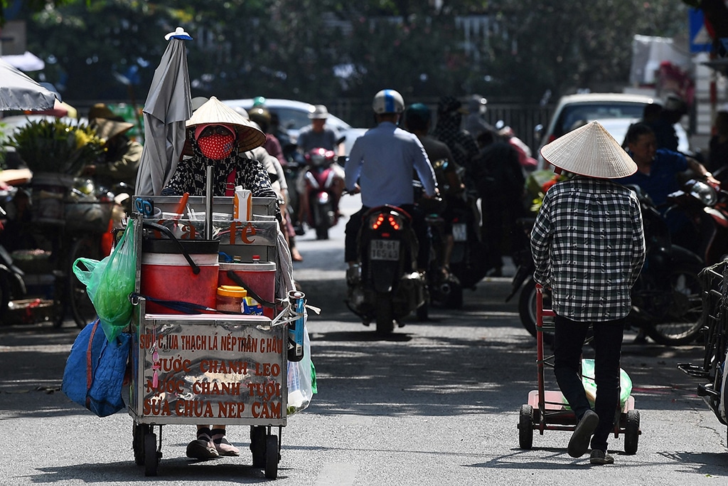 Street vendor Vu Thi Phuong (left) pushes her trolley to sell coffee and soft drinks in Hanoi.