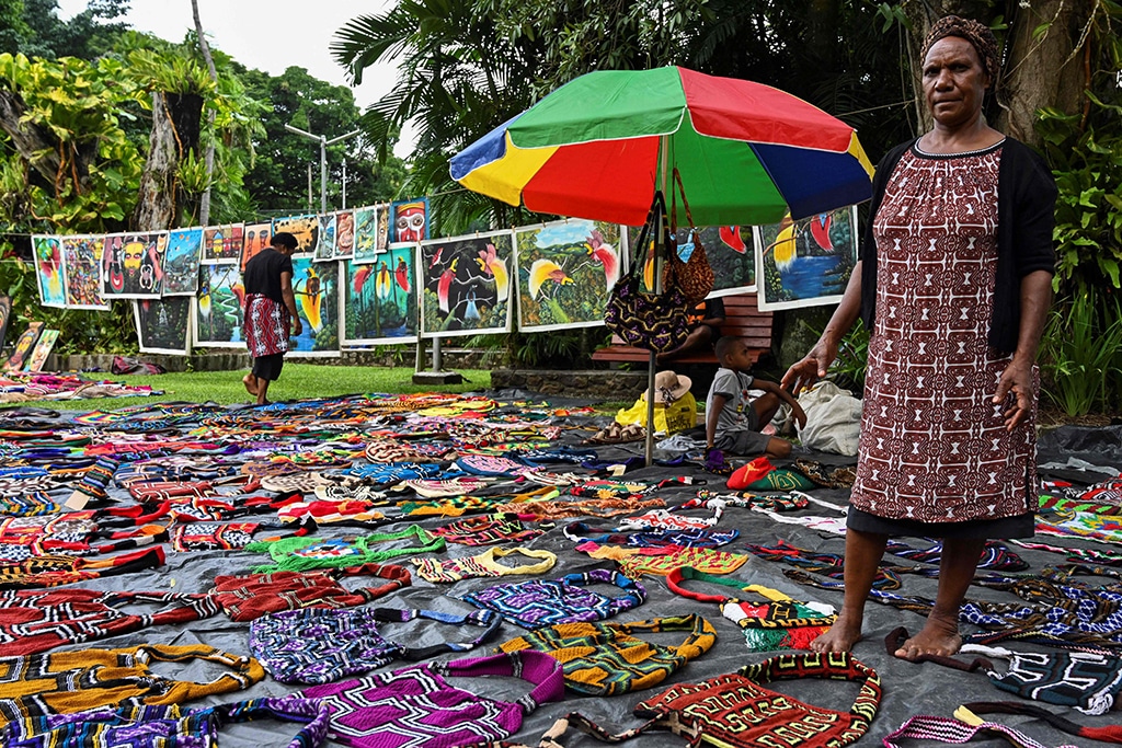 A woman selling traditional Papua New Guinean 'Bilum' bags at a craft market in Port Moresby.