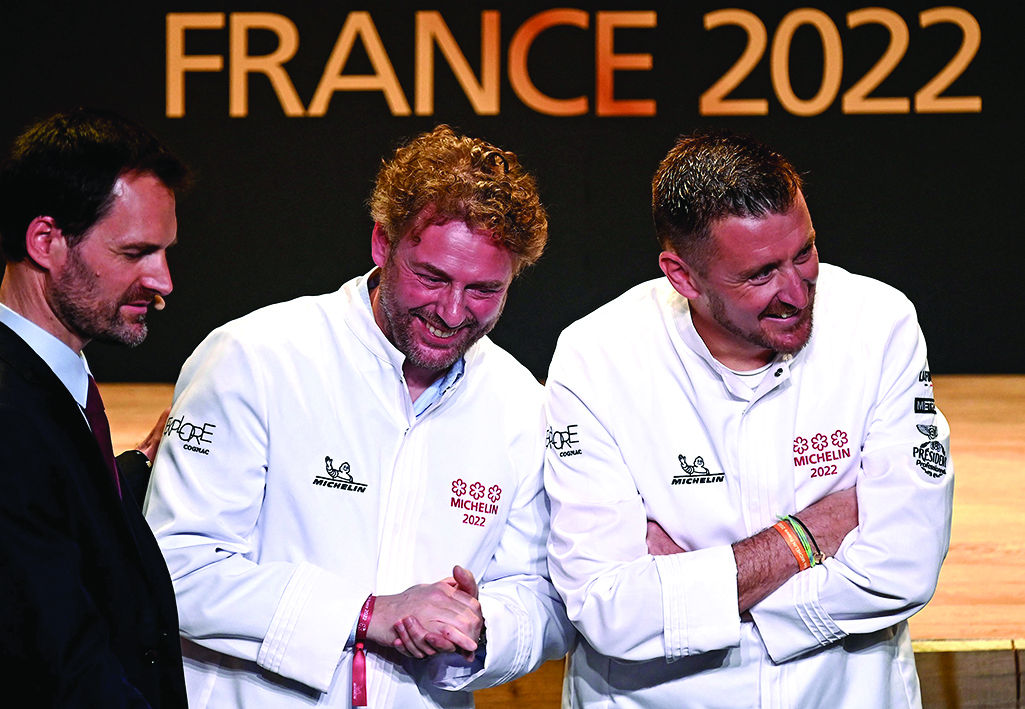 French chef Arnaud Donckele (center) and French chef Dimitri Droisneau (right) celebrate after being awarded a third Michelin star during the 2022 edition of the Michelin guide award ceremony.